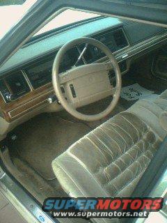 car interior with tan seats and steering wheel, "SUPERMOTORS www.supermotors.net" text at bottom