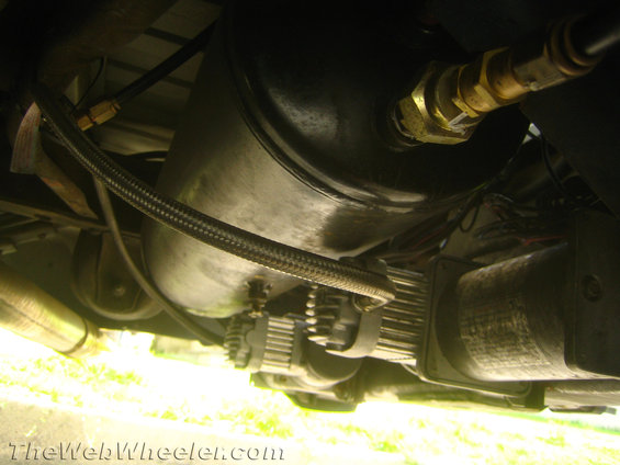 Underside view of an air suspension compressor and tank with braided hoses