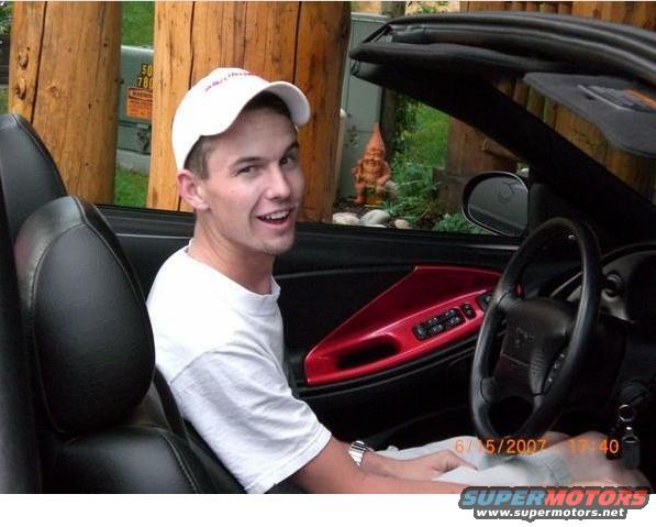 guy in a convertible with red door panel and black seats