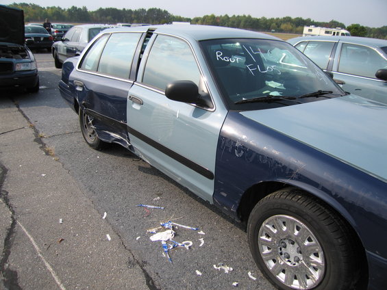 Two-tone blue sedan with dented rear quarter panel and writing on windshield