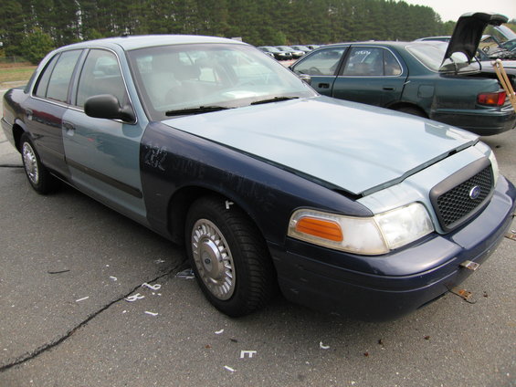 Ford Crown Victoria with mismatched body panels. Hood is up, showing the front grille and headlights