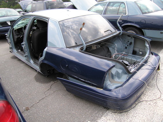 Dark blue sedan rear, disassembled, with open trunk and interior visible