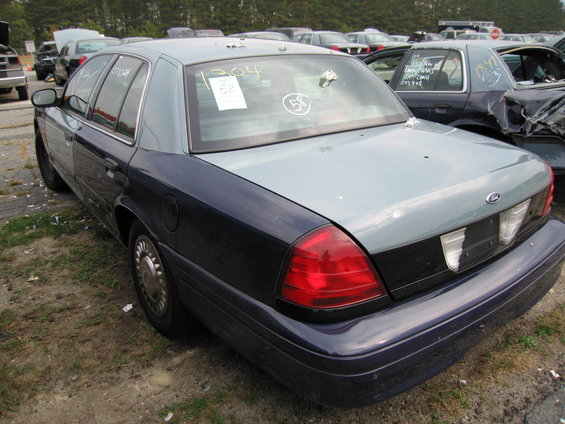Ford Crown Victoria, rear quarter view. It's in a junkyard with other cars