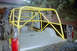 1988 Ford Bronco - Rear view of a black pickup truck modified with a prominent yellow roll cage.