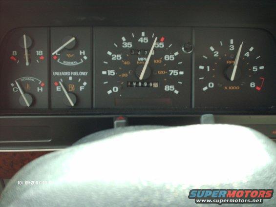 Vehicle dashboard with speedometer, fuel gauge, temperature gauge, and tachometer. Odometer shows 79999