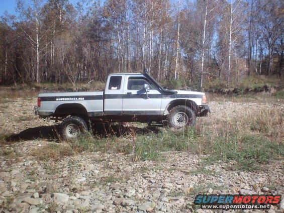 Lifted pickup truck with snorkel parked on rocky ground near trees