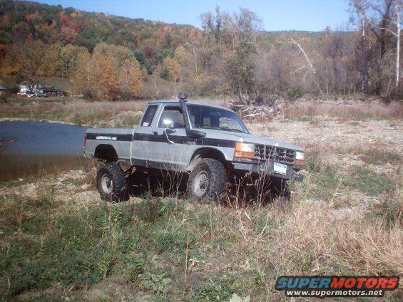Silver 1990 Ford Ranger with snorkel and lift kit parked by a river