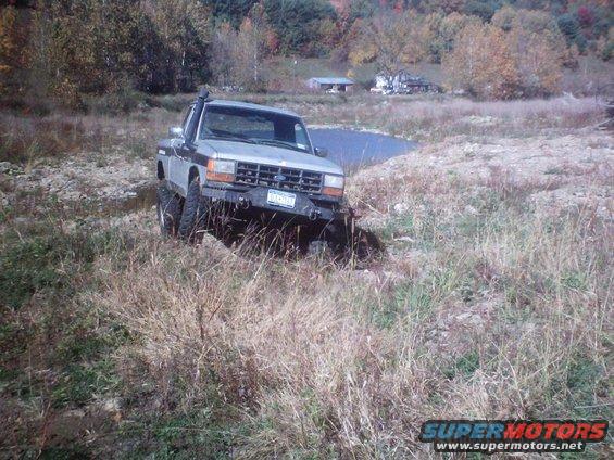 1990 Ford Ranger with snorkel driving through dry grass near a pond