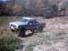 1990 Ford Ranger - A lifted pickup truck navigates a rough, outdoor terrain during autumn.