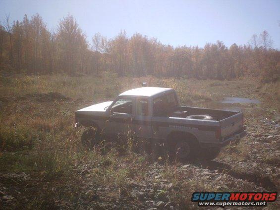 1990 Ford Ranger pickup truck, lifted, in a grassy field with trees