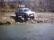 1990 Ford Ranger - A lifted 1990 Ford Ranger pickup truck is parked on the rocky shore of a body of water.
