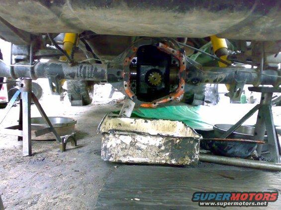Underside of a vehicle on jack stands, showing the rear axle differential with the cover removed