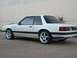 1991 Ford Mustang - A white 1991 Ford Mustang coupe is shown from the rear three-quarter angle, aftermarket wheels and black trim.