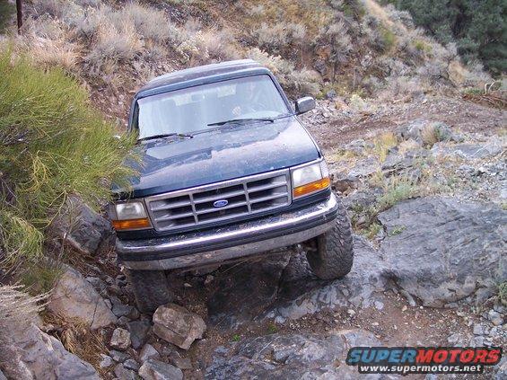 Dark blue SUV with a silver grille driving on a rocky trail