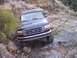 1995 Ford Bronco - A dark blue SUV navigates a challenging rocky terrain on an off-road trail.