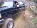 1995 Ford Bronco - A man drives a black Ford Bronco off-road, navigating a rocky, dusty path.