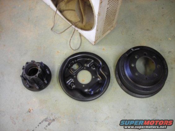 Black brake drum, brake backing plate, and wheel hub assembly on a concrete floor