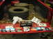 1995 Ford F-250 - The tailgate of a red pickup truck displays various automotive parts, including brake shoes and tires, amidst fallen leaves.