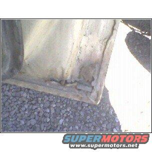 Close-up of a vehicle's lower door frame with visible rust and damage
