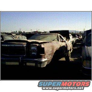 Brown car in junkyard, front quarter view