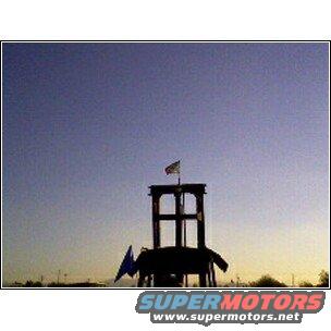 Lifeguard tower with flags against a gradient sky. Supermotors logo visible