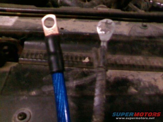 Close-up of two battery cables, one blue with a copper terminal, the other gray and frayed