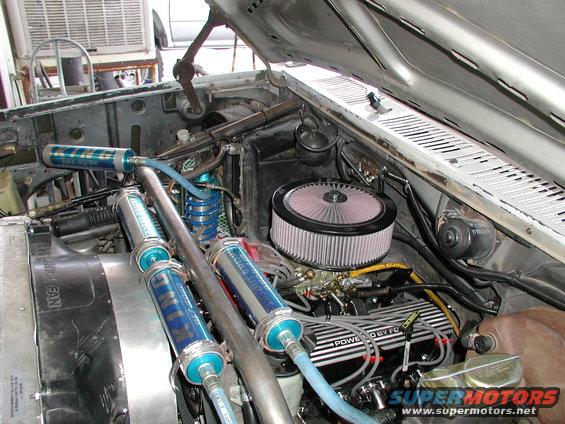 Engine bay with dual nitrous bottles, custom intake, and V8 engine. Some text visible on engine components and bottles