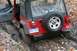 1992 Jeep Cherokee - A red Jeep Wrangler is stuck in a muddy rut, with its rear end visible and a spare tire mounted on the back.