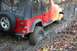 1992 Jeep Cherokee - Red Jeep Wrangler navigating a difficult muddy trail during autumn.