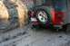 1992 Jeep Cherokee - A red Jeep Wrangler navigates a challenging muddy terrain, with its rear end visible.