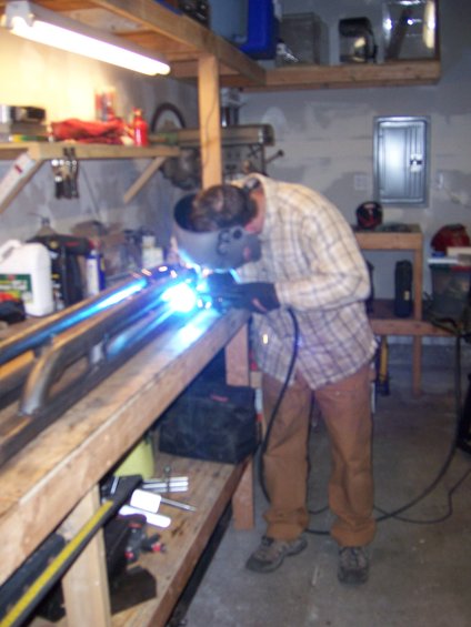 Welder fabricating metal sliders on a workbench