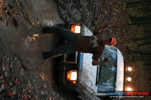 White 1992 Jeep Cherokee stuck in mud, front passenger side visible, person posing on hood