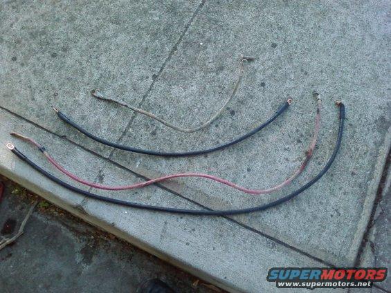 Three automotive battery cables laid out on concrete