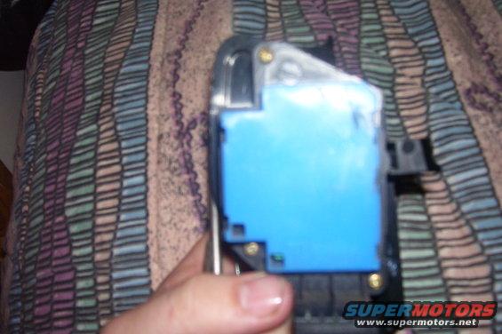 Hand holding a blue automotive electronic component with metal brackets