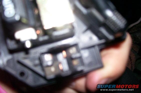 Close-up of a hand holding a black plastic electrical connector with exposed copper terminals