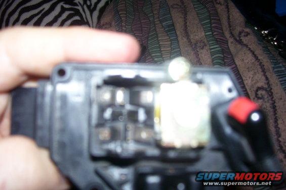 Close-up of an open automotive electrical part with visible circuits and a red button