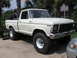 1979 Ford F-150 - A white 1979 Ford F-150 pickup truck with oversized tires is parked on a concrete surface.