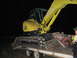1979 Ford F-150 - A yellow excavator is loaded onto a trailer, with a person standing nearby in the dark.