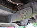 1979 Ford F-150 - The underside of a heavily rusted truck frame, showing structural components and wiring.
