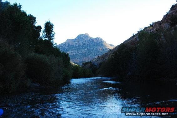 River flows through a canyon with a large mountain in the background under a clear sky