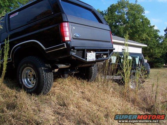 Rear view of black Ford Bronco with custom bumper, parked next to another SUV