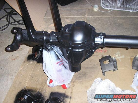 Black differential axle assembly with a white plastic bag underneath. Some parts are scattered around