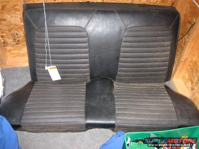 Black car seat with ribbed fabric inserts and vinyl bolsters, hanging tag attached