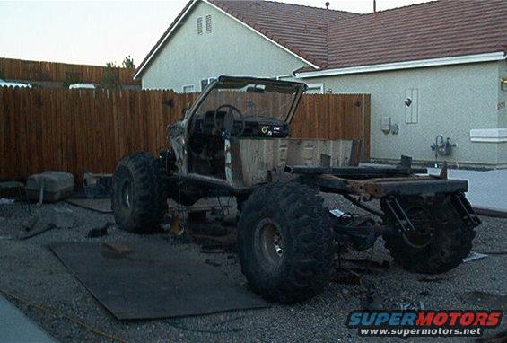 Off-road vehicle chassis with large tires, stripped down in a yard