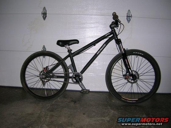 Black Specialized bicycle with disc brakes and Kenda tires, parked indoors