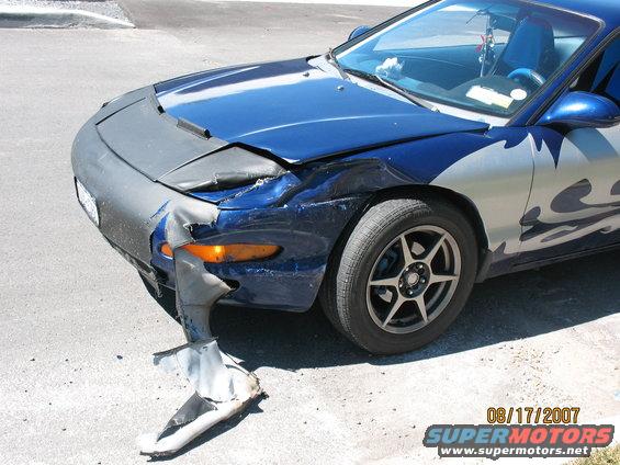 Blue car with a torn bumper and damaged fender. It has silver flame decals on the side