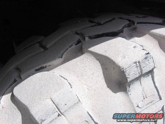 Close-up of a large tire tread with deep grooves and some wear