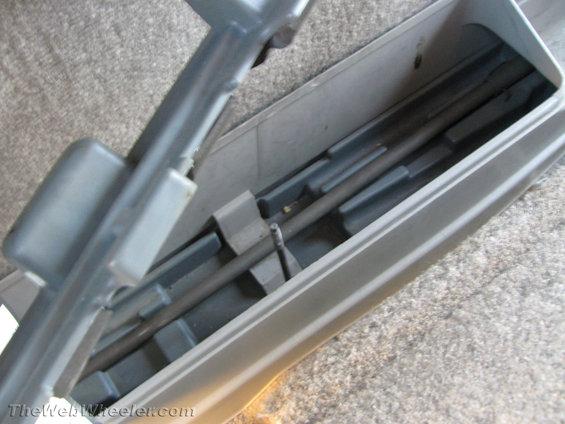 Gray plastic truck bed storage compartment with a metal rod inside, viewed from above