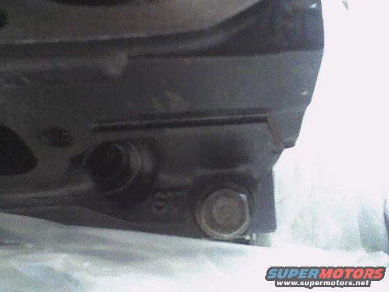 Close-up of a dark metal engine block casting with bolts