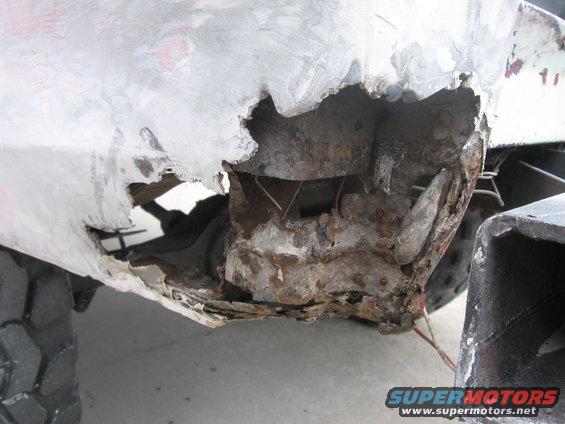 Heavily rusted and damaged vehicle body panel, showing extensive corrosion and structural compromise